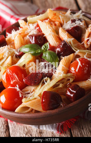 Penne pasta con salsiccia e pomodori in una ciotola macro. In verticale Foto Stock