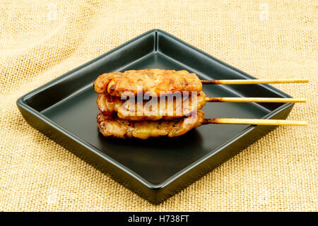 In stile tailandese barbecue di carne di maiale in piastra nera su un letto di sacco Foto Stock