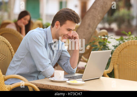 L'uomo a guardare i contenuti multimediali in un computer portatile in un ristorante Foto Stock