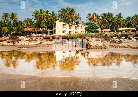 Pensioni e lettini sulla riva del mare Arabico nel mezzo di rocce e di arenaria in Ashvem, Goa, India Foto Stock