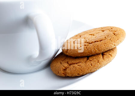 Dettaglio di due biscotti allo zenzero con tazza e piattino. Sfondo bianco. Foto Stock