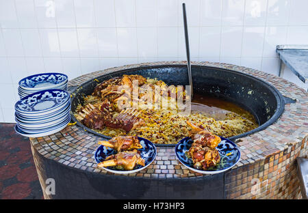 Il grande calderone pilaf (qozon) e piatti a base di carne di agnello in cucina all'aperto del centro asiatica di Plov Center Foto Stock