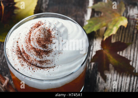 In casa vacanza dessert di mousse di zucca con panna montata su legno tavolo rustico contro lo sfondo di foglie di autunno Foto Stock