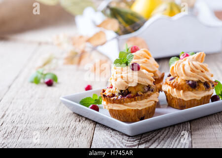 Autunno fatti in casa a base di mirtillo palustre tortini di zucca con glassa di formaggio cremoso su tavola in legno rustico Foto Stock