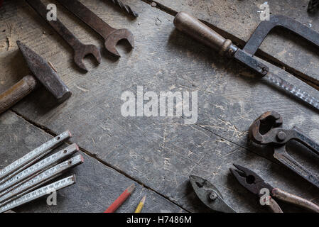 Vecchi strumenti sulla vecchia bottega, tavolo in legno, Hummer, misurare, sega, chiave, tele, matite Foto Stock