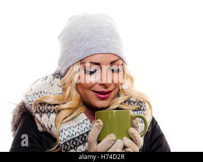 Un attraente donna bionda vestita per l'inverno sta cercando la sua tazza. Foto Stock