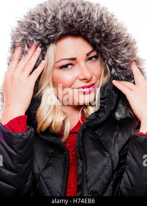 Una donna attraente è fotografato indossando un cappotto invernale con il cofano su uno sfondo bianco. Foto Stock