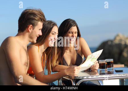 Amici in vacanza la consultazione di una guida in un hotel terrazza Foto Stock