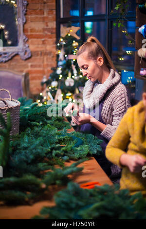 Madre e figlia di decorazione ghirlanda di conifere. Celebrazione della Messa di Natale concept Foto Stock