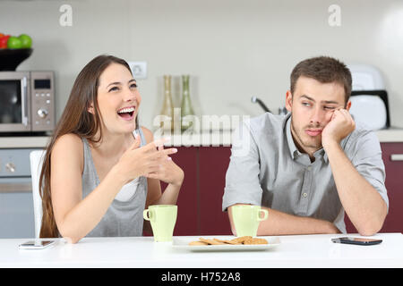 Annoiato marito udienza di sua moglie a parlare durante la colazione nella cucina di casa Foto Stock