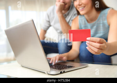 In prossimità di un paio di acquisti on line con carta di credito e un laptop seduto su un divano nel soggiorno di casa Foto Stock