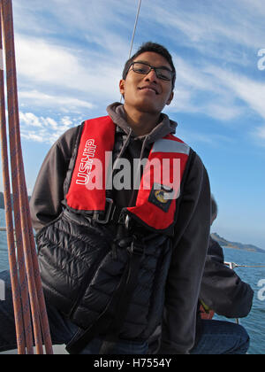Giovane uomo al timone di una barca a vela, Binic ,Cotes-d'Armor, Bretagne, Bretagna Francia Foto Stock