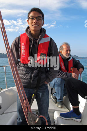 Giovane uomo al timone di una barca a vela, Binic ,Cotes-d'Armor, Bretagne, Bretagna Francia Foto Stock