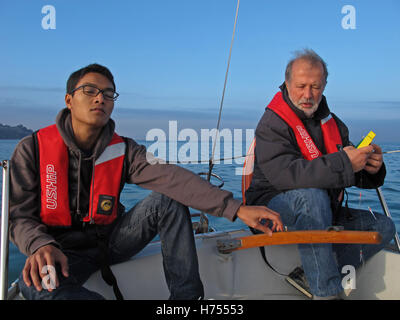 Giovane uomo al timone di una barca a vela, Binic ,Cotes-d'Armor, Bretagne, Bretagna Francia Foto Stock