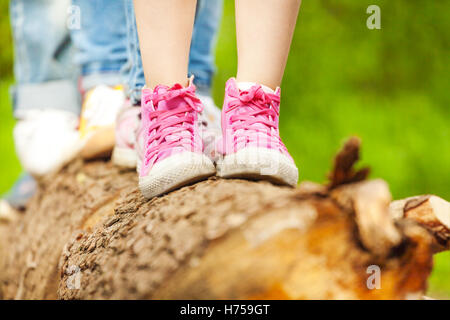 Bambini i piedi in rosa sneakers in piedi su un log Foto Stock