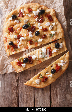 Focaccia con pomodori secchi, feta e olive sul tavolo. vista verticale da sopra Foto Stock