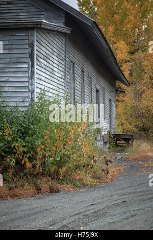 Un vecchio edificio in legno dal lato di una linea ferroviaria. Foto Stock