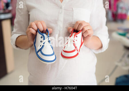 Irriconoscibile incinta Donna Scarpe shopping per il suo bambino Foto Stock