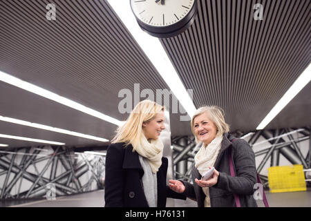 Due belle donne in piedi alla piattaforma della metropolitana, talkin Foto Stock