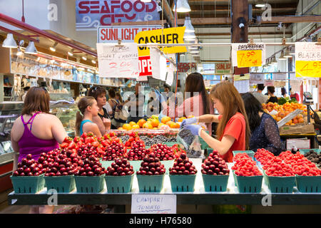 Vancouver, Canada: Vendor in sacchi di mirtilli freschi per un cliente al sole aziende agricole a Granville Island mercato pubblico. Foto Stock