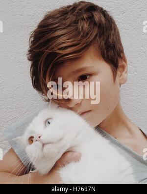 Ragazzo cuddling il suo gatto di casa con diversi occhi colorati Foto Stock