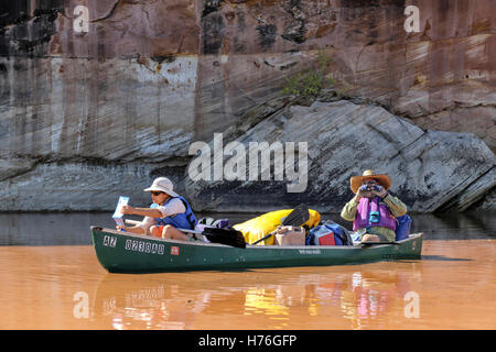 Di mezza età giovane pagaie una canoa lungo il fiume verde nel Parco Nazionale di Canyonlands dopo un allagamento in caso di pioggia. Foto Stock