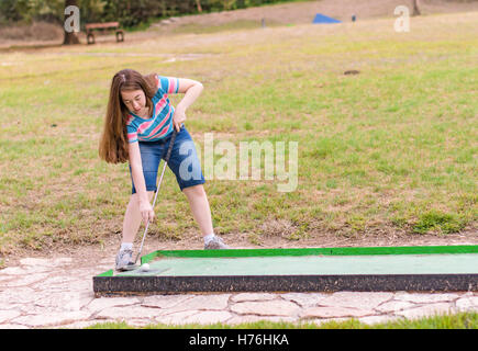 Giovane donna giocando outdoor golf in miniatura in una foresta di Galilea nel nord di Israele Foto Stock