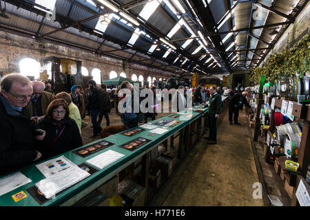 CAMRA beer festival nel vecchio capannone locomotiva a Tunbridge Wells, Regno Unito. La gente la selezione di birre provenienti da vari fusti, barili di birra, a lungo dietro un contatore. Foto Stock