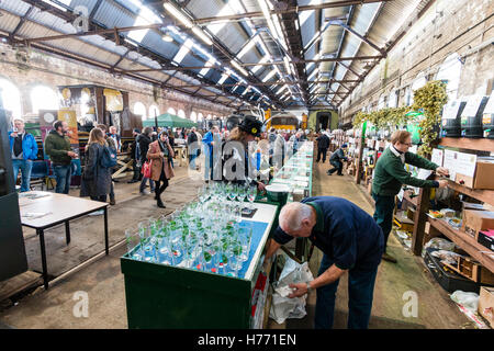 CAMRA beer festival nel vecchio capannone locomotiva a Tunbridge Wells, Regno Unito. La gente la selezione di birre provenienti da vari fusti, barili di birra, a lungo dietro un contatore. Foto Stock