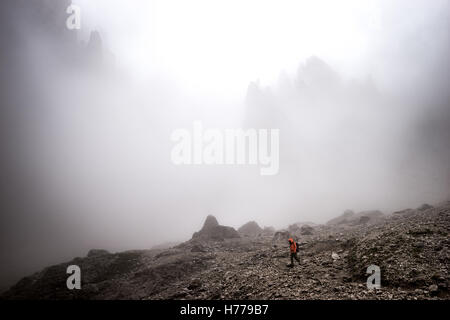 L'uomo escursionismo nella nebbia nelle Dolomiti, Val Gardena, nel Sud Italia Foto Stock