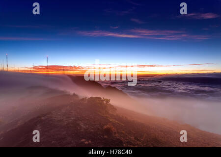 Tramonto in un picco coperti dalla nebbia con le antenne radio in background Foto Stock