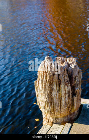 Vecchio e molto ben utilizzati mooring bollard polo o alla fine di un molo. Spazio di copia in acqua. Foto Stock