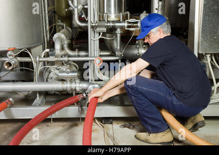 Lavoratore Specializzato del montaggio di un impianto di pompa in un'impresa industriale Foto Stock
