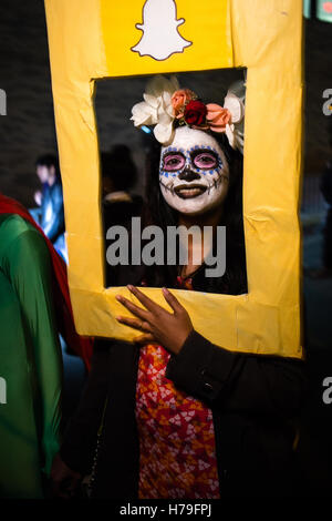 New York, NY - 31 ottobre 2016. Una donna con la faccia dipinta come la Calavera Catrina dietro un telaio Snapchat nella Villa di Greenwich Foto Stock