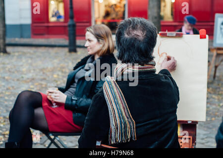 Parigi, Francia - 4 Novembre 2015: una giovane donna che pongono all uomo l'artista di strada il 4 novembre 2015 a Montmartre. Pittore fa un s Foto Stock