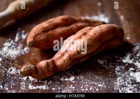 Primo piano di alcune patate dolci su di un legno rustico tavolo da cucina Foto Stock