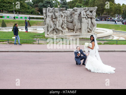 Coppie in viaggio di nozze in posa per le fotografie di nozze nei pressi della Torre Eiffel a Parigi, Francia Foto Stock