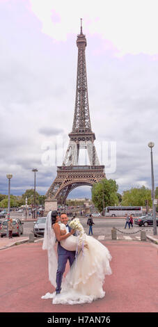 Coppie in viaggio di nozze in posa per le fotografie di nozze nei pressi della Torre Eiffel a Parigi, Francia Foto Stock