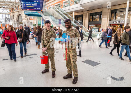 La stazione di Waterloo, Londra, Regno Unito. 3 Novembre, 2016. Due membri della Royal Marines raccogliere donazioni come la banda delle guardie granatieri esegue per pendolari e passeggeri sul piazzale della Stazione Waterloo di Londra, Regno Unito. La loro performance è stata a sostegno dell'annuale Royal British Legion appello di papavero. Credito: Graham Prentice/Alamy Live News Foto Stock