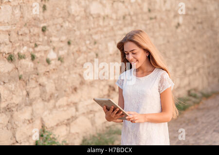 Giovane donna graziosa utilizzando computer tavoletta al di fuori di un edificio Foto Stock