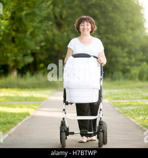 La nonna di spingere un passeggino in posizione di parcheggio Foto Stock