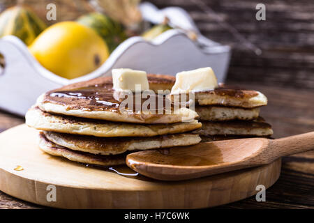 Frittelle fatte in casa servite calde con burro e sciroppo d'acero su tavola in legno rustico Foto Stock