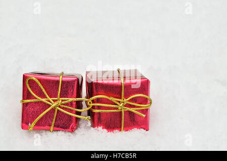 Due piccoli rosso metallico parcelle luminoso sulla neve sfondo, vicino, spazio per il testo, orizzontale Foto Stock