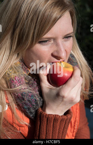 Attraente donna bionda di mordere in un Apple Foto Stock