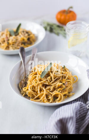 Una ciotola di mezze mangiate Crema di zucca fraiches pasta con la salvia è fotografata dalla vista frontale. Foto Stock