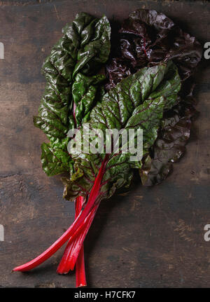 Bietole novelle mangold foglie di insalata su un vecchio legno scuro dello sfondo. Vista da sopra con spazio per il testo. Mangiare sano tema. Foto Stock