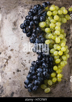 I grappoli di ripe rosso bagnato e uve bianche su vecchie texture di sfondo di metallo. Vista da sopra con spazio per il testo Foto Stock