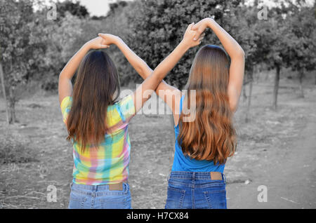 Migliori amici per sempre - due, 12 anni, ragazze adolescenti tenendo le mani in un infinito per sempre segno per indicare BFF - colore su blac Foto Stock