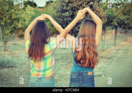 Migliori amici per sempre - due, 12 anni, ragazze adolescenti tenendo le mani in un infinito per sempre segno per indicare BFF - look vintage Foto Stock