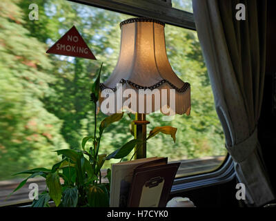 Pullman di prima classe ferroviaria vano di corsa con il vecchio stile lampada sul tavolo da pranzo con menu e velocità sfondo sfocato Foto Stock